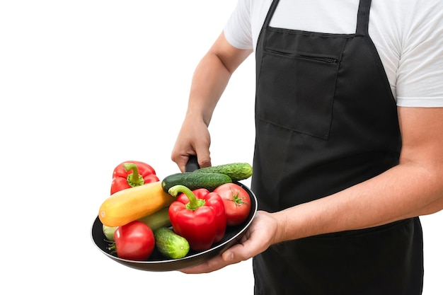 Sartén con verduras frescas en manos de un cocinero aislado en un fondo blanco