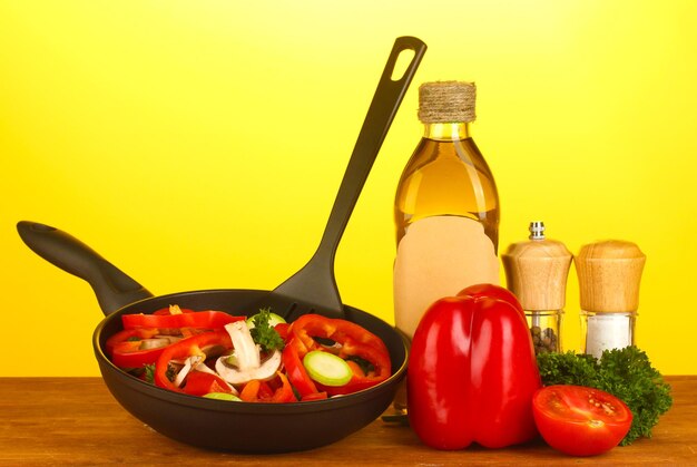 Foto sartén con verduras sobre un fondo amarillo