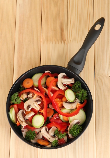 Sartén con verduras sobre fondo de madera