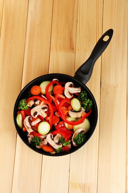 Sartén con verduras sobre fondo de madera