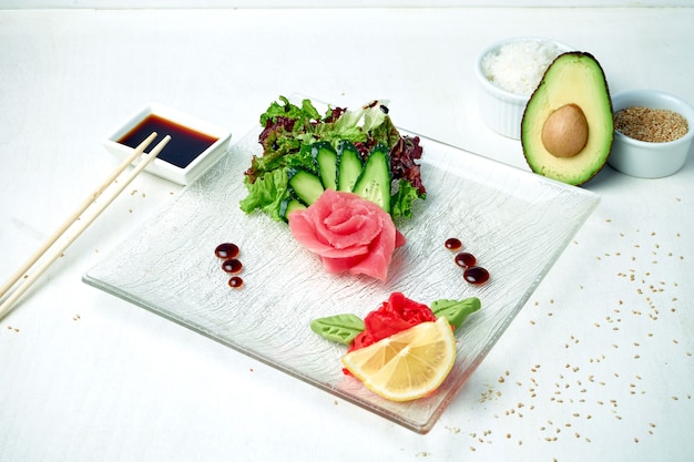 Sashimi japonés clásico - atún con ensalada en un plato blanco en una composición con ingredientes