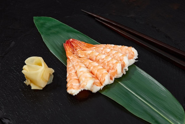 Sashimi mit Garnelen auf Bambusblatt auf schwarzem Hintergrund