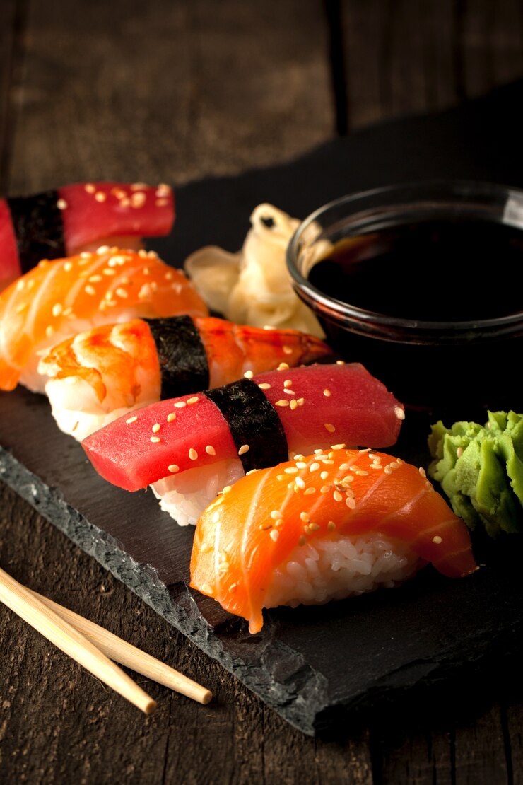 Foto sashimi y rollos de sushi en un tablero de piedra