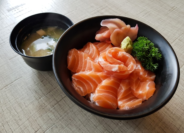 Sashimi de salmón con arroz y sopa de miso en la mesa de madera.