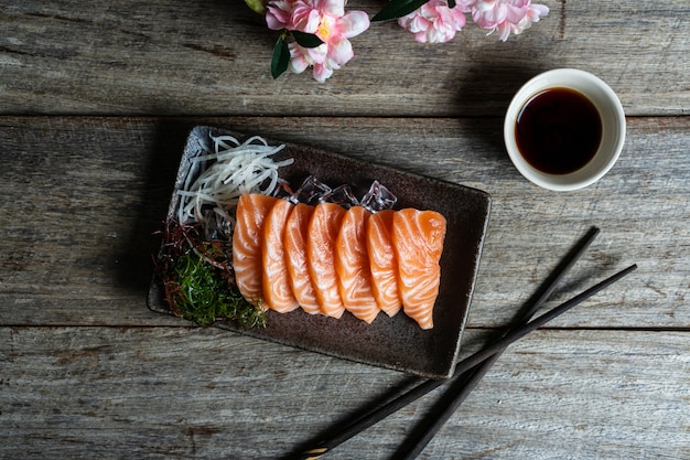 Sashimi de salmón comida japonesa con salsa de soja en mesa de madera