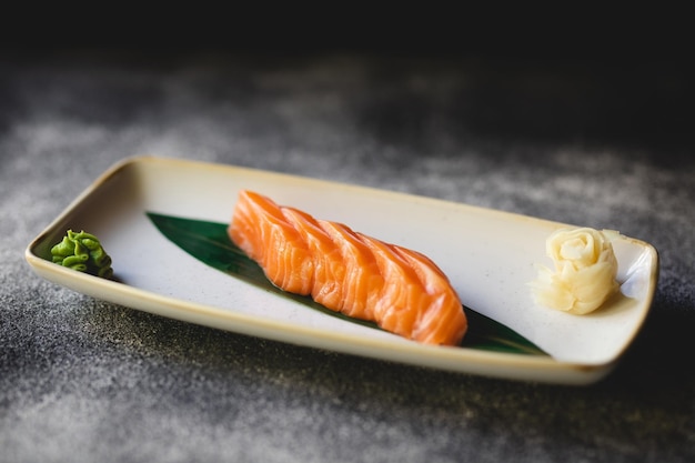 Sashimi de salmón sobre un elegante fondo oscuro. Servicio. Camarero. Banquete