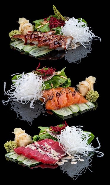 Sashimi-Set mit Lachs, Aal und Thunfisch auf schwarzem, glänzendem Hintergrund mit Reflexion, dekoriert mit gemischtem Salat