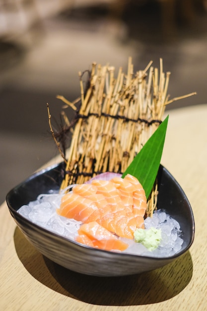 El sashimi en un tazón negro consiste en salmón (sake) puesto en hielo - concepto de comida japonesa.