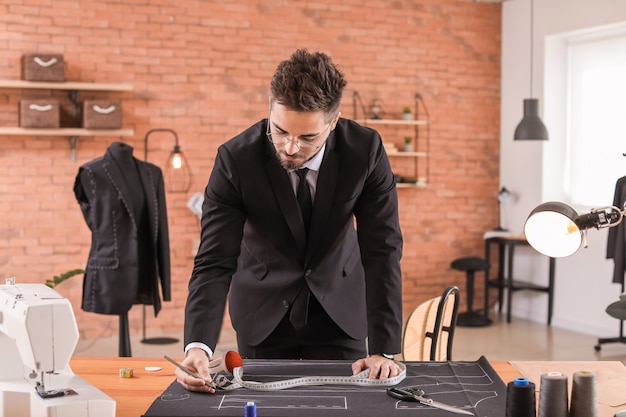 Foto sastre joven trabajando en la mesa en el atelier