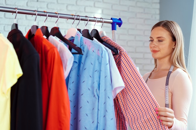 Sastre de mujer comprobando la ropa terminada en su oficina.