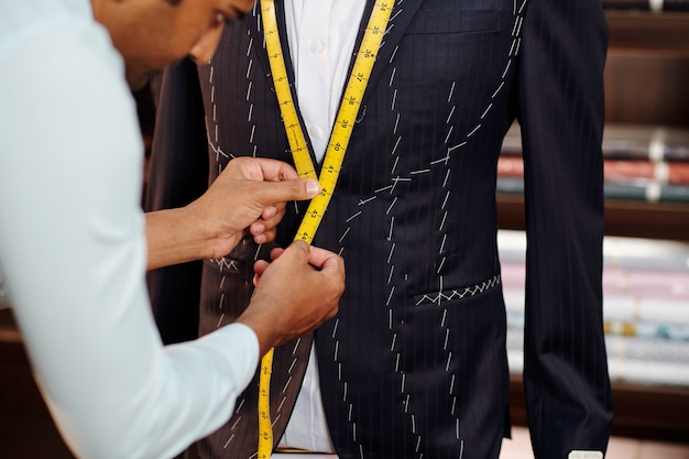 Foto sastre profesional confeccionando traje a medida para cliente en su moderno estudio