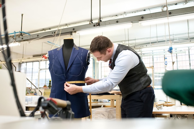 Sastre que mide la chaqueta incompleta en un maniquí