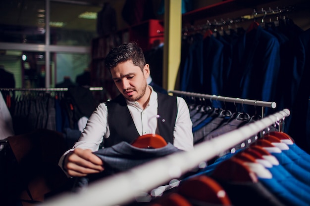 Sastre, sastrería. Traje de hombre, sastre en su taller. Elegantes trajes de hombre colgando en fila. Trajes clásicos de lujo para hombre en el estante en la elegante boutique de hombres.