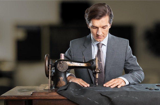 Sastre en el trabajo. Seguro joven sastre cosiendo ropa en la sastrería