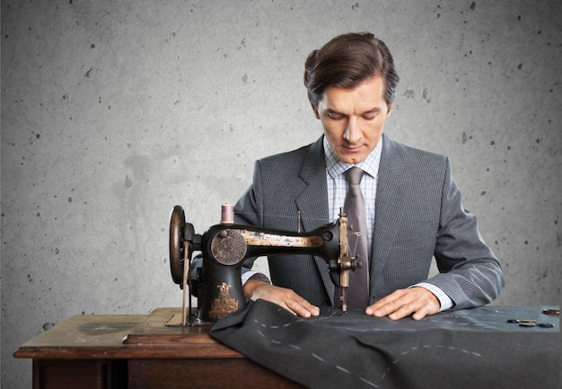 Sastre en el trabajo. Seguro joven sastre cosiendo ropa en la sastrería