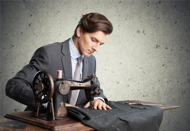 Sastre en el trabajo. Seguros de joven sastre cosiendo ropa en la sastrería