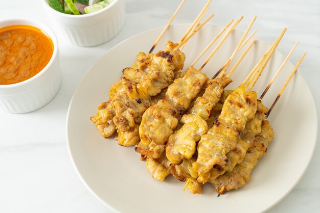 Satay de cerdo con encurtidos de salsa de maní que son rodajas de pepino y cebolla en vinagre - estilo de comida asiática