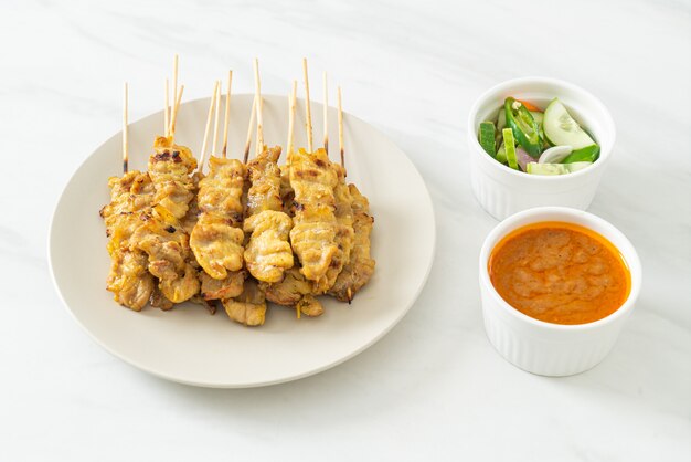 Satay de cerdo con encurtidos de salsa de maní que son rodajas de pepino y cebolla en vinagre - estilo de comida asiática