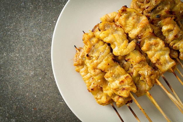 Satay de cerdo con encurtidos de salsa de maní que son rodajas de pepino y cebolla en vinagre - estilo de comida asiática