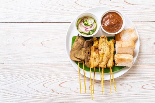 Satay de cerdo con salsa de maní y encurtidos