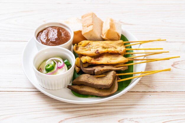 Satay de cerdo con salsa de maní y encurtidos