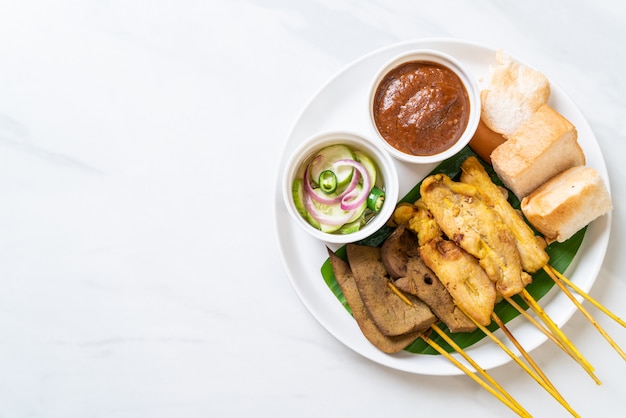 Satay de cerdo con salsa de maní y encurtidos