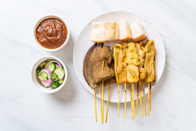 Satay de cerdo con salsa de maní y encurtidos