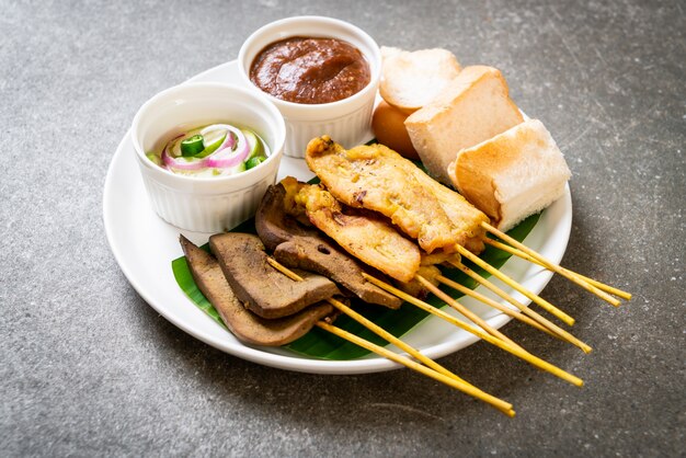 Satay de cerdo con salsa de maní y encurtidos