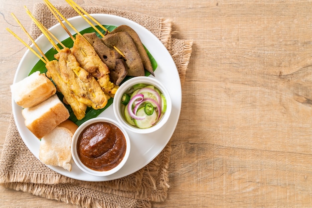 Satay de cerdo con salsa de maní y encurtidos