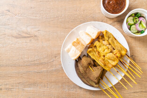 Satay de cerdo con salsa de maní y encurtidos