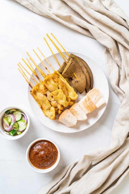 Satay de cerdo con salsa de maní y pepinillos