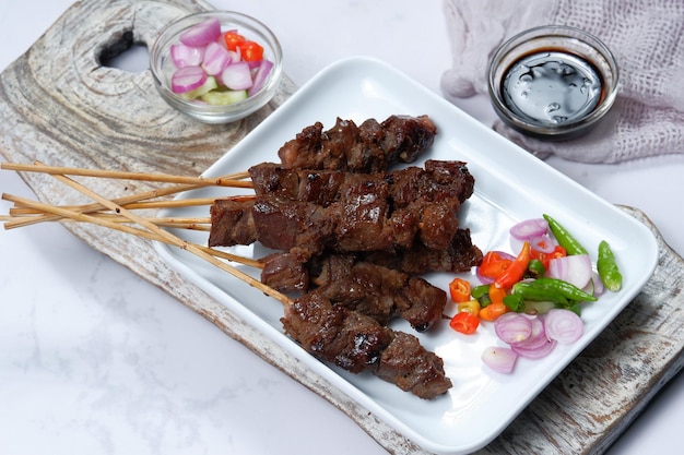 satay o sate brocheta de carne a la parrilla, servida con ensalada picante, pepino, chile y salsa de soya,