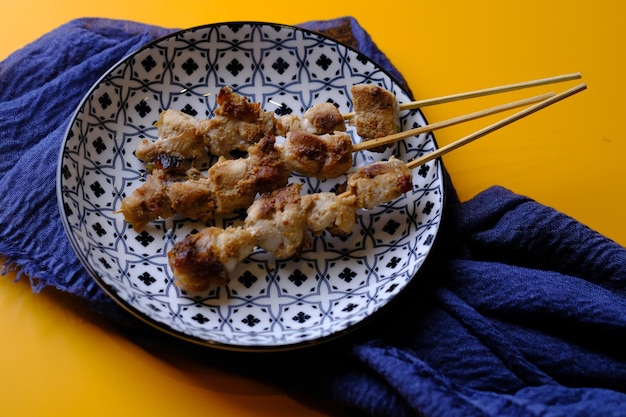 sate ikan atum. satay de atum servido no prato de cerâmica na mesa amarela. Comida indonésia. proteína animal.