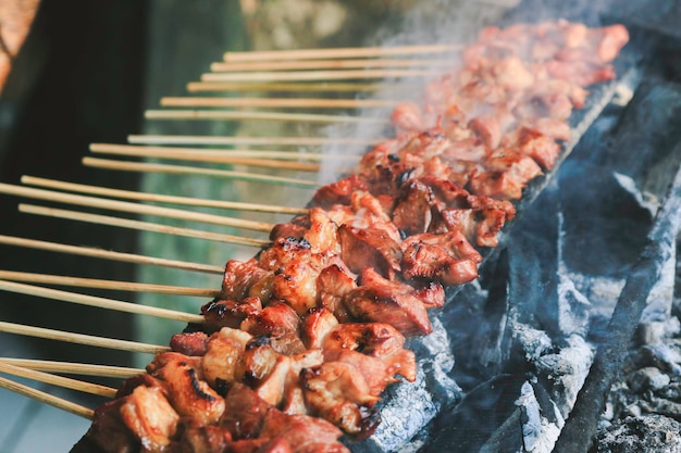 Sate Kambing o satay de cabra en fuego rojo asado por personas