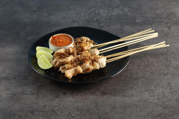 Sate Taichan, gegrillter Hähnchen-Satay mit Salz und Röstzwiebeln. Auf Teller serviert mit Sambal (Chili)