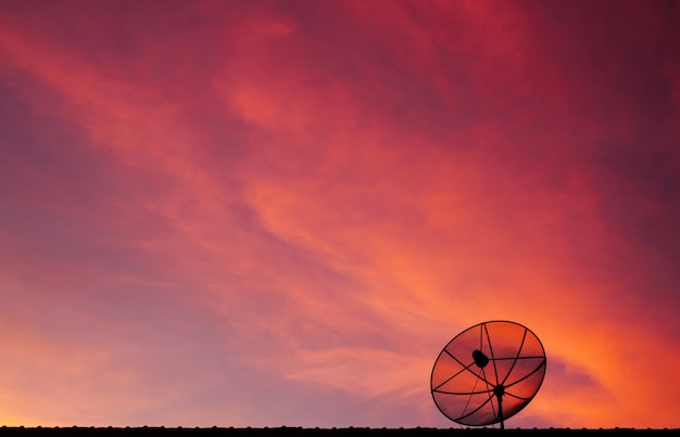 Satellitenschüssel auf buntem twilight Himmelhintergrund