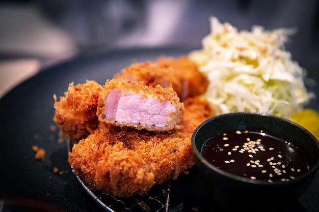 Satisfactorio tradicional japonés Tonkatsu de cerdo frito con corte de chuletón con pepinillos y repollo, servido en una