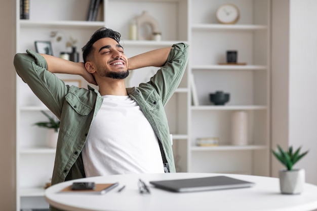 Satisfecho y atractivo hombre árabe milenario con barba se toma un descanso y descansa y disfruta mucho en