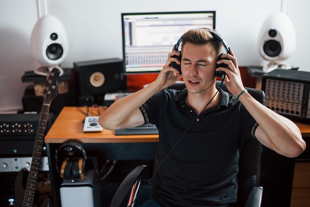 Satisfecho con la calidad del audio. Ingeniero de sonido en auriculares trabajando y mezclando música en interiores en el estudio.