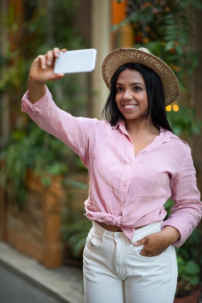 Satisfeita turista negra milenar de chapéu tirando selfie no telefone gravando vídeo para o blog, divirta-se