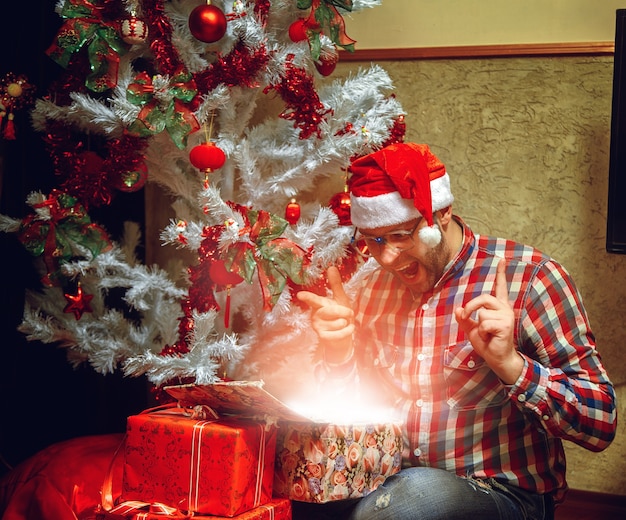 Satisfeito com seu hipster presente de Natal no chapéu de Papai Noel. Espírito de natal. Ano Novo.