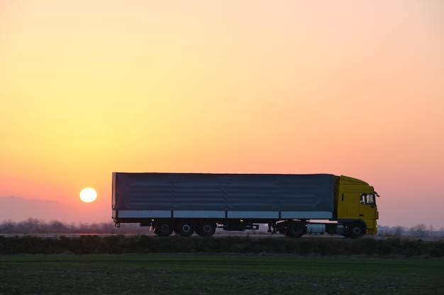 Sattelschlepper mit Frachtanhänger, der abends auf der Autobahn fährt und Güter transportiert Liefertransport- und Logistikkonzept