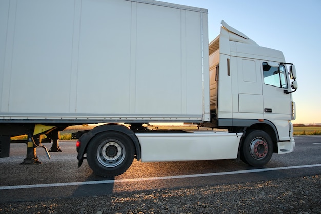 Sattelschlepper mit Frachtanhänger, der abends auf der Autobahn fährt und Waren transportiert. Liefertransport- und Logistikkonzept.