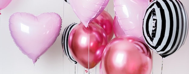 Satz Ballone in Form eines Herzens und des runden Rosas und auf hellem Hintergrund mit Kopienraum gestreift.