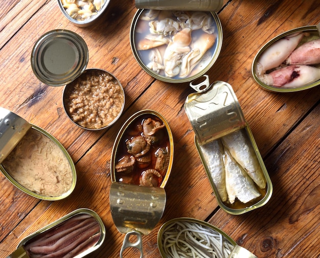 Satz Dosen mit Fisch und Meeresfrüchten auf hölzernem Hintergrund, Draufsicht Beschneidungspfad eingeschlossen