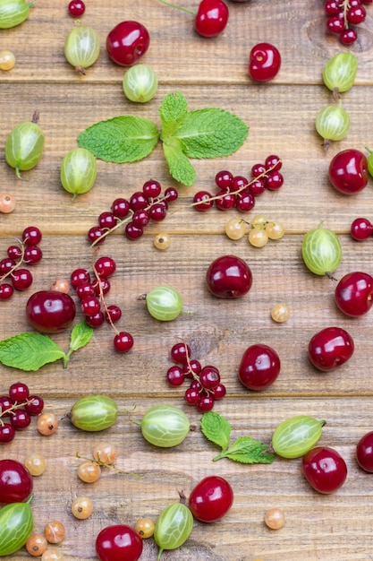 Satz frische Beeren, Kirschen, Johannisbeeren und Stachelbeeren auf hölzernem Hintergrund. Beerenhintergrund. Flach legen