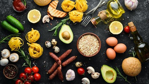 Foto satz gesunde lebensmittel tomaten pasta gewürze gemüse und würstchen draufsicht schwarzer steinhintergrund