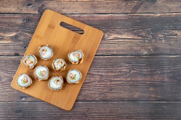 Satz heiß gebratene Sushi-Rollen mit Lachs auf Holzbrett.