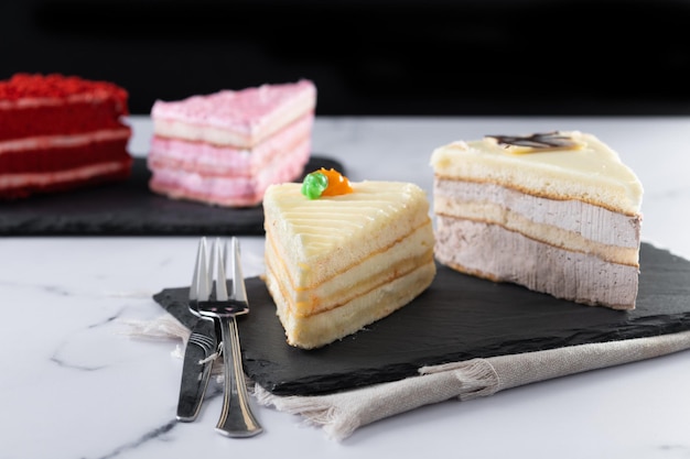 Satz Kuchenportionen Samt-Erdbeerkuchen, Karottenkuchen und Schokoladenkuchen auf MarmorxA