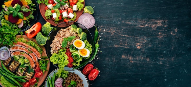 Satz Lebensmittel Hähnchenbrust gegrillte Würstchen Auberginen Kirschtomaten frisches Gemüse Auf einem schwarzen Holztisch Draufsicht Freier Platz für Text